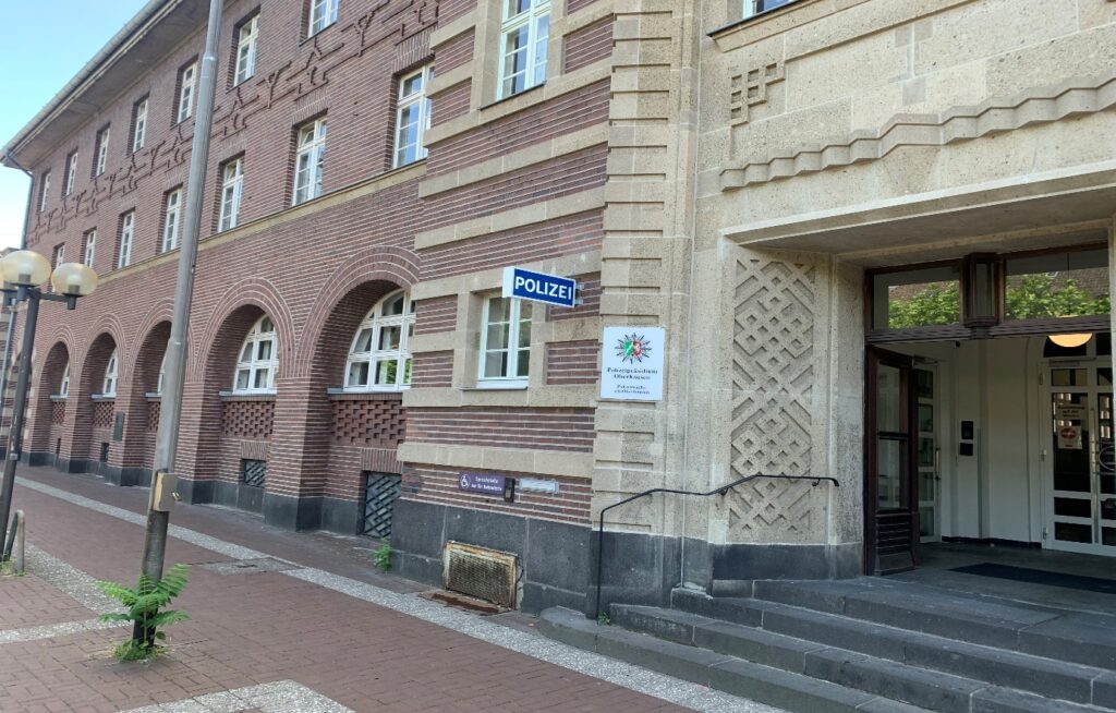 Eingangsbereich Dienstgebäude des Polizeipräsidium Oberhausen am Friedensplatz mit 4 Stufen und im Gebäude zurückspringendem Eingangsbereich. Es ist der Haupteingang des großen 3-geschossigen Gebäudes mit rotem Backstein und hellen Fugen.